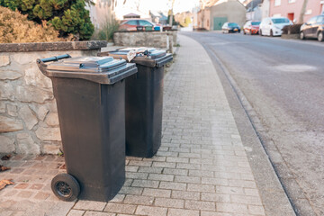 Naklejka premium Two plastic garbage containers standing on the street.