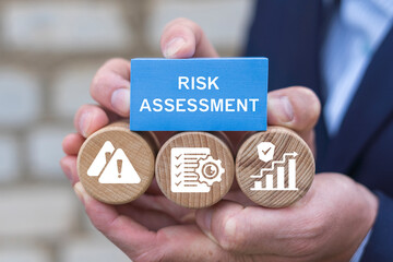 Risk Assessment Business Financial Management concept. Businessman holding blocks with icons sees the inscription RISK ASSESSMENT. Risky evaluation.