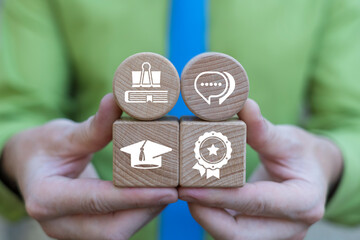 Business person holding wooden blocks with icons symbolizing: conceptual modern education. Learning and education concept.