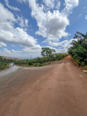 A road junction in Rwanda surrounded by tropical banana plantations and green hills under a cloudy sky.