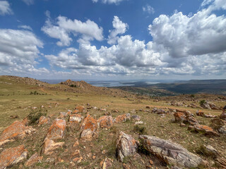 High angle view of rocky Rwandan landscape with orange boulders overlooking a valley and distant lake.
