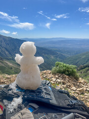 Small handmade snowman sitting on the seat of an adventure motorcycle in the snowy Djurdjura mountains of Algeria.