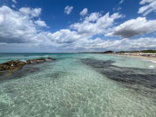 Transparent turquoise sea water and rocky coastline on a sandy beach in Puglia, Southern Italy.