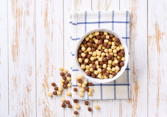 ceramic bowl of tasty corn rings and strawberry rings on a light kitchen table, top view. Copy space for text.