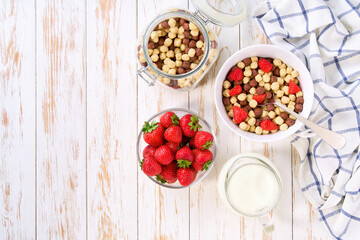Quick breakfast for kids, corn balls with two flavors and strawberry on a light kitchen table, top view.