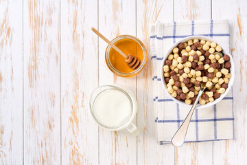 bowl of tasty cereal with fruit flavors with milk and honey on a light kitchen table.Top view. healthy sweet snack for breakfast.