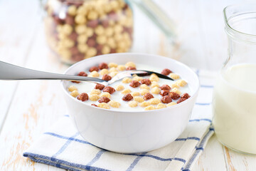 Making a healthy breakfast corn balls and chocolate corn balls and milk on a white table.