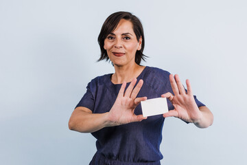 portrait of adult latina woman holding a card in blank on blue background in Mexico Latin America, or hispanic senior brunette female 