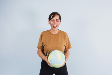 portrait of adult latina woman holding a volleyball ball on blue background in Mexico Latin America, or hispanic senior brunette female in sportswear