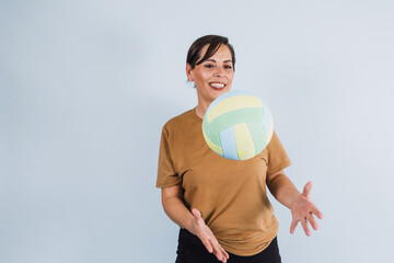 portrait of adult latina woman holding a volleyball ball on blue background in Mexico Latin America, or hispanic senior brunette female in sportswear