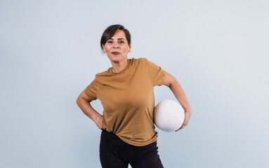 portrait of adult latina woman holding a soccer ball on blue background in Mexico Latin America, or hispanic senior brunette female in sportswear