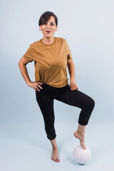 portrait of adult latina woman holding a soccer ball on blue background in Mexico Latin America, or hispanic senior brunette female in sportswear