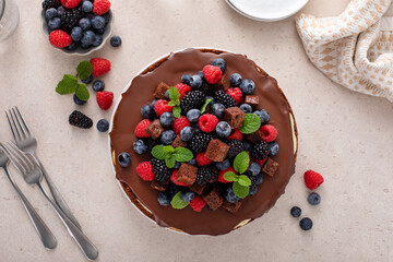 Traditional cheesecake topped with chocolate ganache and fresh berries and brownie bites