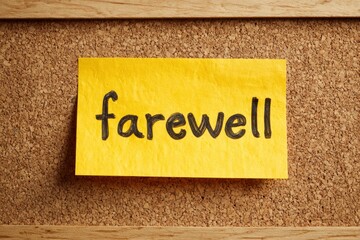 A vibrant yellow note, featuring the distinct handwritten word "farewell" in bold black letters, is prominently affixed to a textured cork board, framed by natural wood accents. This clear, close-up i