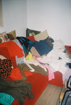 Large Pile of Messy Laundry and Clothes on a Red Sofa

