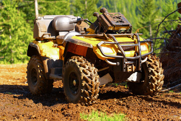 Yellow ATV covered in mud in a forest on a sunny day © Hamilton Productions