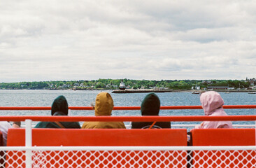 People with hoods on riding a ferry boat in Maine