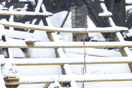 Graphic impression of burned down barn covered in snow after a blizzard snowstorm with the black wood and construction carcas contrasting against the white winter landscape