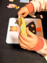 A child's small hands pick up and apply magnetic clothing elements to a picture of a girl on a board