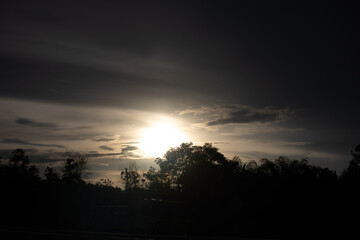Sunset sky with silhouetted trees and clouds at dusk