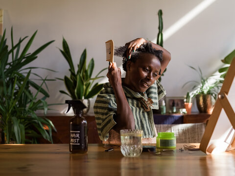 Woman Grooming Hair at Home Surrounded by Plants