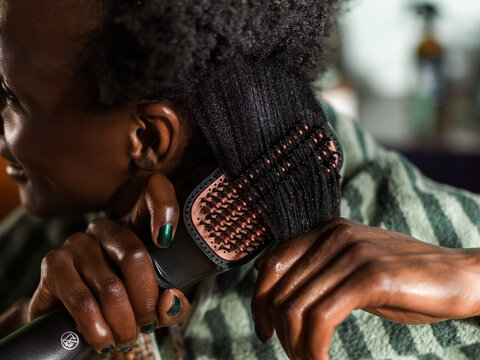 Black woman using hair styler 