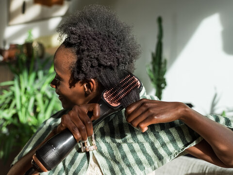 Woman using electric hair styler 