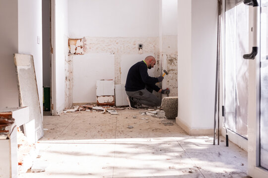 Workman demolishing wall at office worksite 