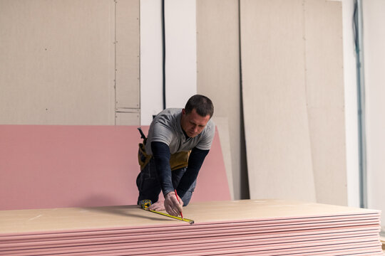 Professional drywaller marking gypsum board 