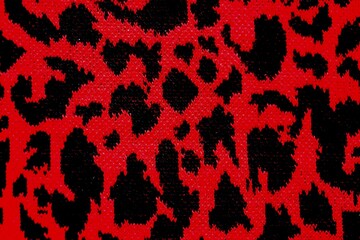 Knitted wool pattern with a leopard design. Fabric and textile with leopard pattern and in red and black. Textured background for paper or different kind of pattern.