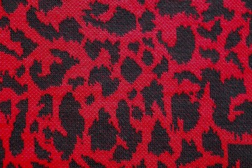 Knitted wool pattern with a leopard design. Fabric and textile with leopard pattern and in dark red and black. Textured background for paper or different kind o fpattern.