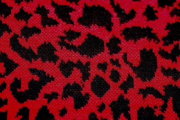 Knitted wool pattern with a leopard design. Fabric and textile with leopard pattern and in red and black. Textured background for paper or different kind of pattern.	