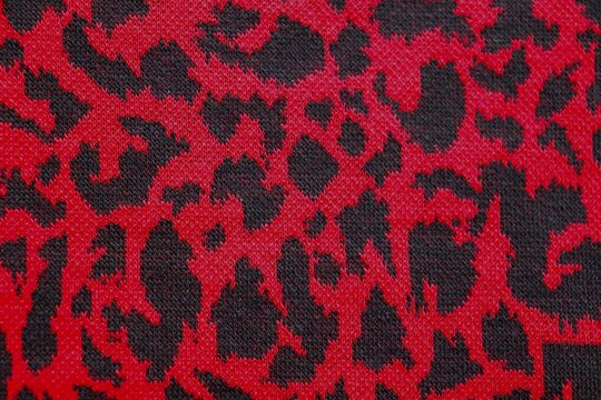 Knitted wool pattern with a leopard design. Fabric and textile with leopard pattern and in dark red and black. Textured background for paper or different kind o fpattern.