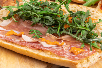 An open face Italian prosciutto hams and salami sandwich on a long submarine panini bun