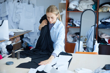 Woman clothing creators meticulously examine textile positioning and pattern matching