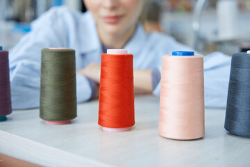 Craftswoman surrounded by colorful threads and machines.