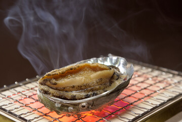 煙り立ち昇る七輪でアワビを焼く