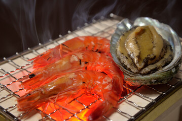 煙り立ち昇る七輪でアワビと海老を焼く