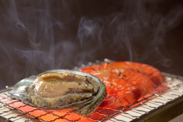 煙り立ち昇る七輪でアワビと海老を焼く