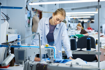 Young seamstress inspecting and ensuring quality of industrial sewing work