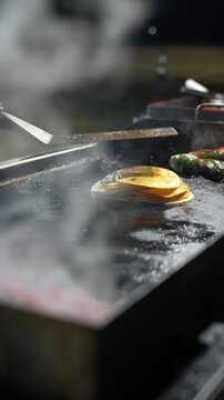 Slow-motion vertical video of tortillas placed on a grill, steam lifting into the air to showcase warmth, texture, and simple food preparation for taco making -Taco Stand Series - Food vendor