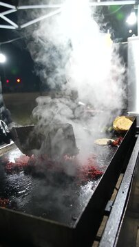 Slow-motion footage of al pastor pork grilling outdoors, with rising steam that emphasizes texture, heat, and authentic Mexican street food cooking - Taco Stand Series - Food vendor