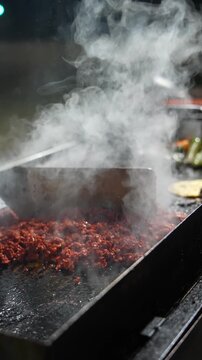 Hot al pastor meat sears on a grill in slow motion, steam lifting into the air and immersing viewers in the aromas and rhythm of Mexican outdoor taco culture - Taco Stand Series - Food vendor