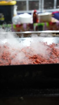 Juicy al pastor pork sizzles on a hot grill in slow motion as steam billows upward, evoking bold aromas and the vibrant atmosphere of Mexican street taco cooking - Taco Stand Series - Food vendor