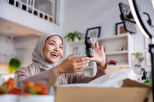 Woman in hijab selling products to online audience.