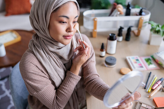 Muslim woman applies makeup at vanity
