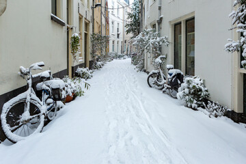 Snow in alleyway street of historic Dutch city center Zutphen, The Netherlands, with thick pack white precipitation after blizzard. Winter wonderland picturesque scene
