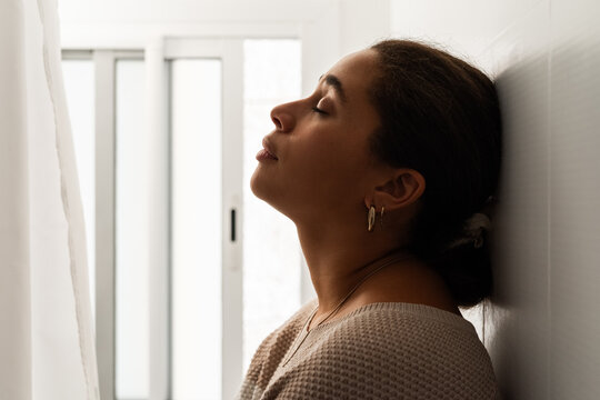 Woman Resting Against Wall With Eyes Closed 