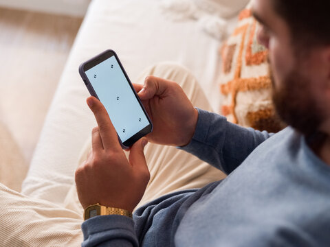 Man Using Smartphone While Relaxing on a Couch at Home