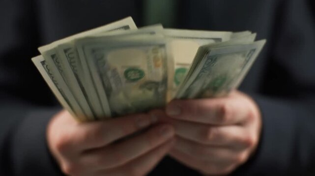 Hands carefully counting a large stack of crisp dollar bills, symbolizing financial success, personal wealth, and the tangible rewards of successful economic endeavors